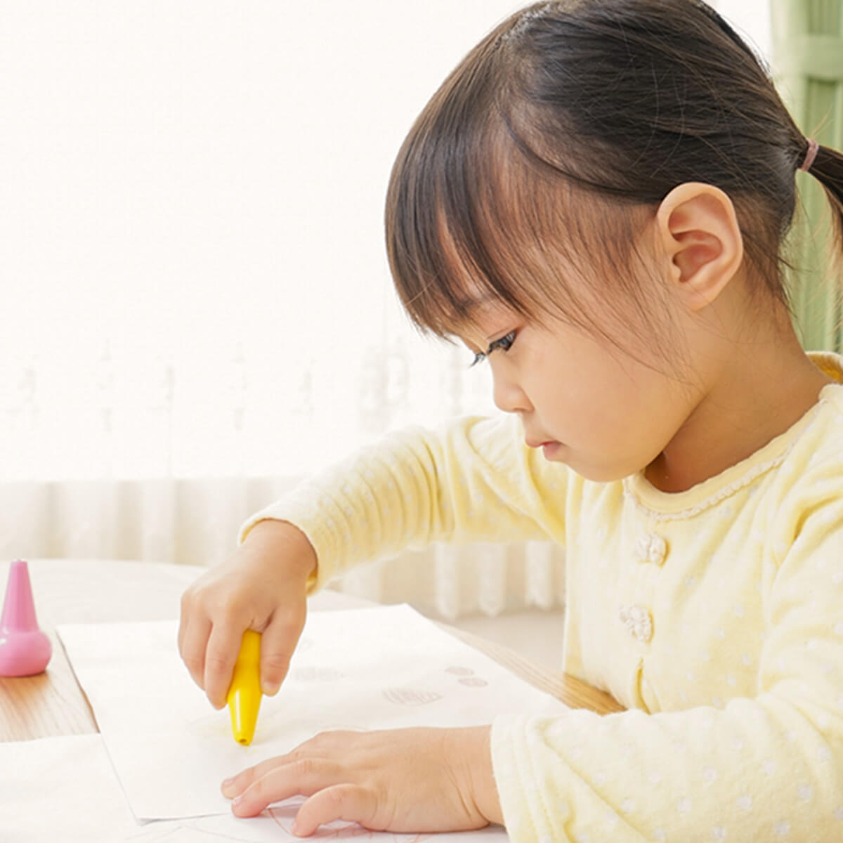 集中してクレヨンで描画に取り組む女の子のクローズアップ写真。