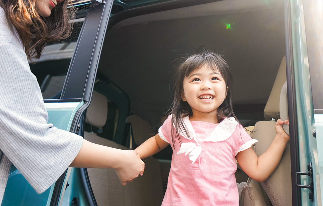 車から降りる際に、大人の手に掴まりながら笑顔で車外を見つめる女の子